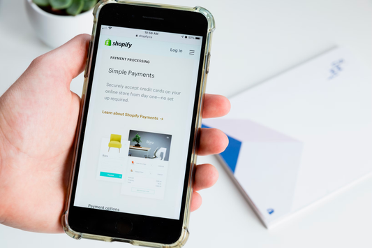 a person holding a smartphone showing Shopify page for payments